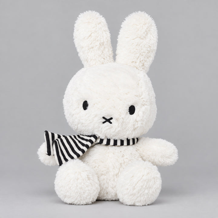 White Miffy bunny soft toy sitting with a black and white striped scarf, featuring long upright ears and soft fluffy fur.