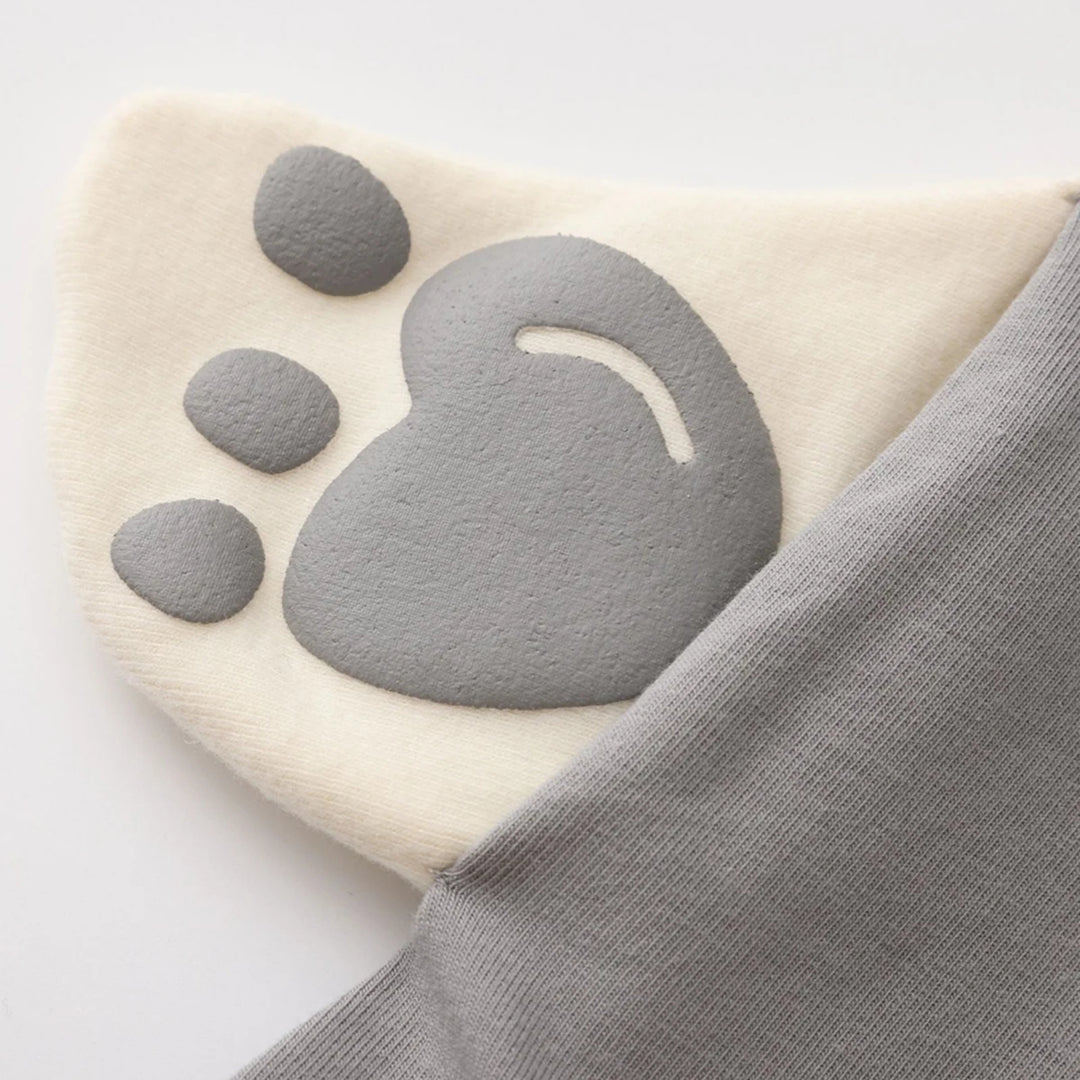 Close-up of the cream 3D bear paw detail with grey paw pads attached to the side of the grey romper.