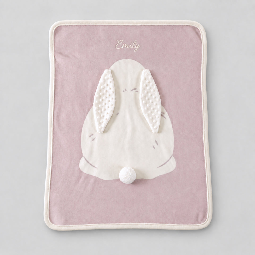 Pink bunny blanket with a large white bunny applique, textured ears, pom-pom tail, and the name “Emily” embroidered in white at the top.