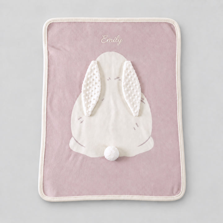 Pink bunny blanket with a large white bunny applique, textured ears, pom-pom tail, and the name “Emily” embroidered in white at the top.