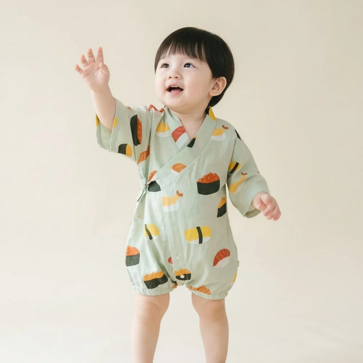Light green kimono-style baby romper with colourful sushi prints, wrap-front tie detail, short sleeves and snap closures.