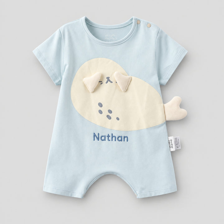 Light blue short-sleeve baby romper with a cream seal applique, 3D flippers and tail detail, personalised with the name “Nathan.”