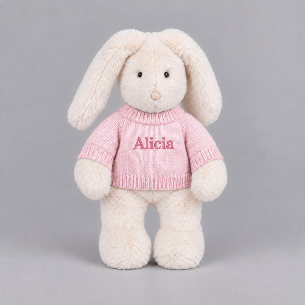 Personalised cream bunny soft toy wearing a pink knitted jumper embroidered with the name Alicia.