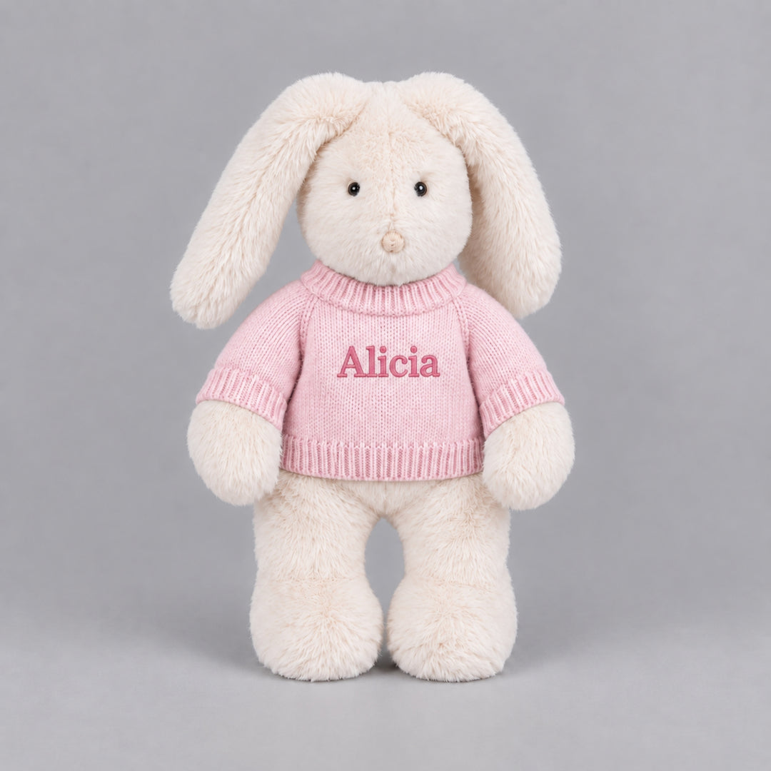 Personalised cream bunny soft toy wearing a pink knitted jumper embroidered with the name Alicia.