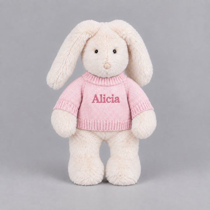 Personalised cream bunny soft toy wearing a pink knitted jumper embroidered with the name Alicia.