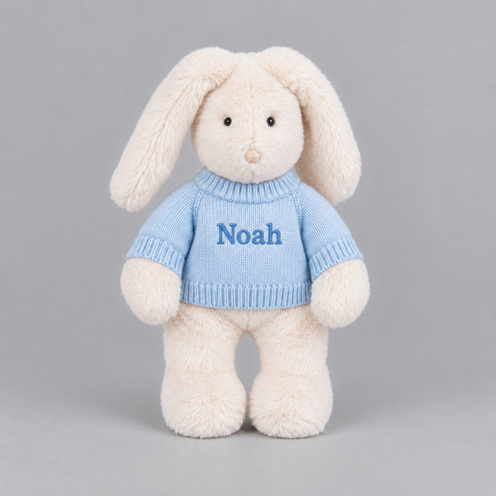 Personalised cream bunny soft toy wearing a blue knitted jumper embroidered with the name Noah.