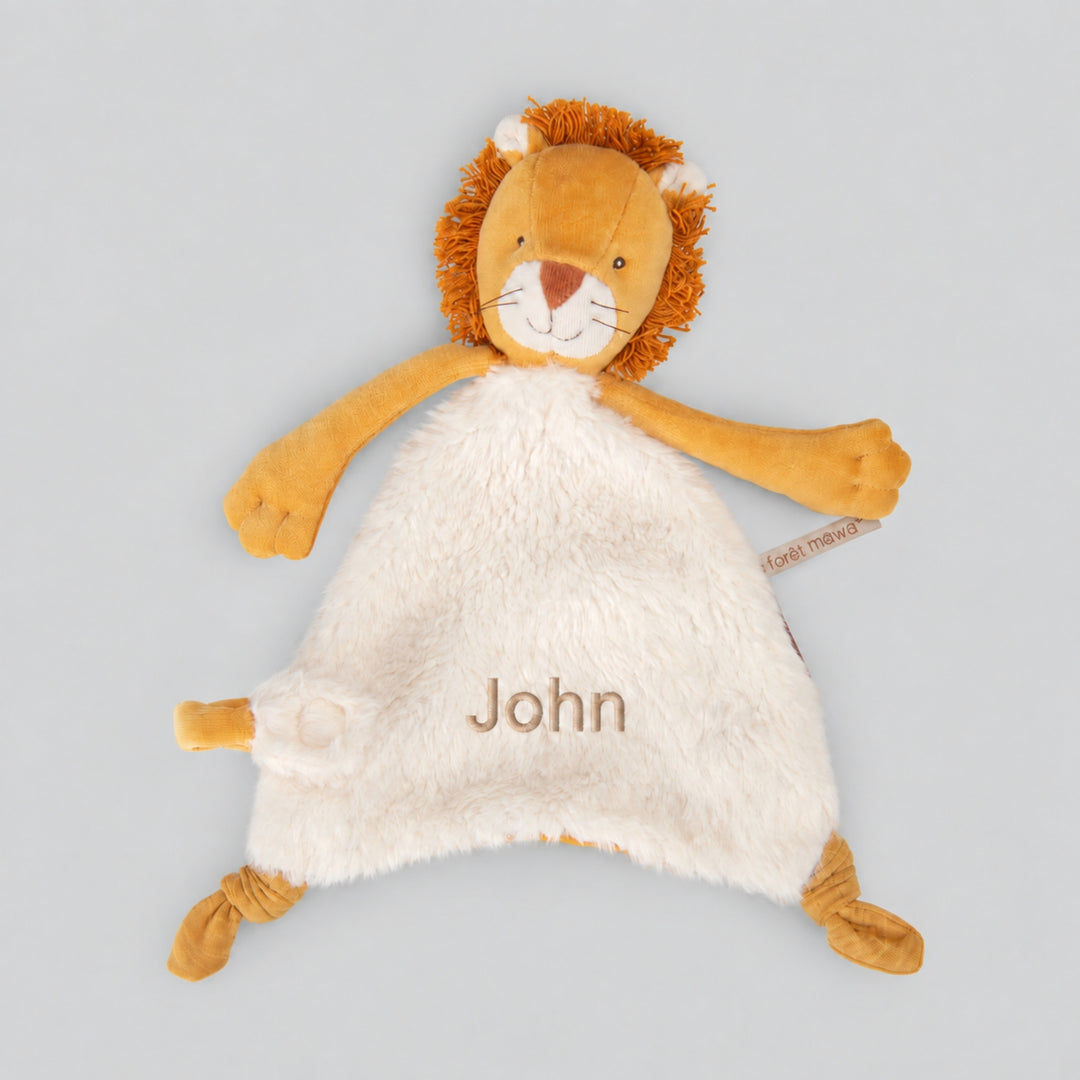 Personalised Moulin Roty Mamba Lion comforter with mustard lion details, cream plush fabric and the name “John” embroidered on the front.