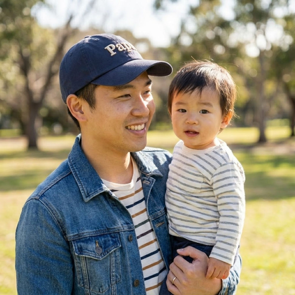 Father wearing Navy cap embroidered with "Papa" and carrying his son