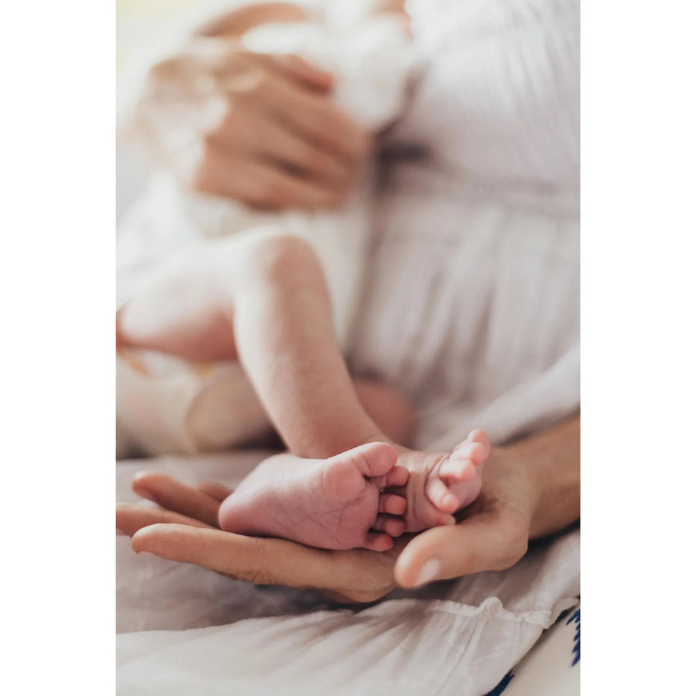 Close-up of a baby's feet held in an adult's hands, with a blurred background, a newborn shoot photographed by Katie Martin-Sperry Photography