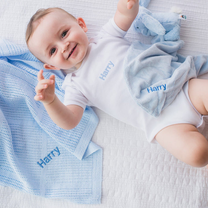 Baby with blue organic cotton blanket with "Harry" personalised in blue thread