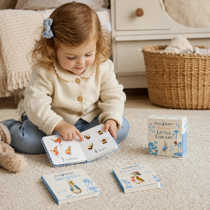 Child playing with educational books on a carpeted floor