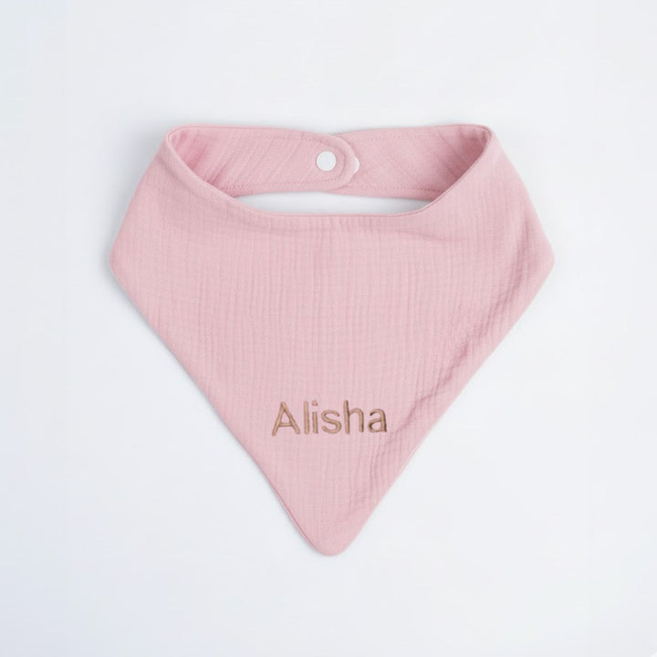 Pink baby bib with 'Alisha' embroidered on a light gray background