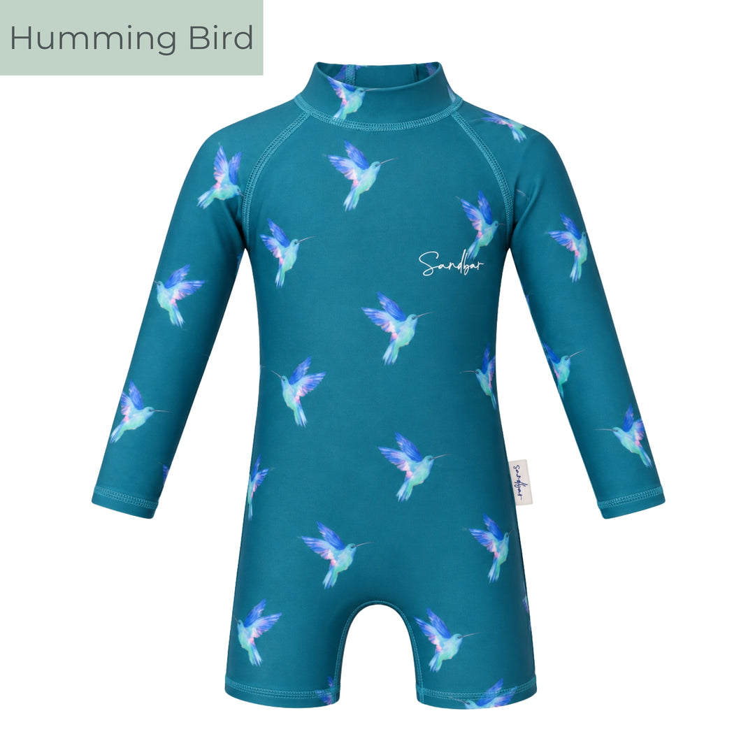 Teal long-sleeve baby swimsuit with colourful hummingbird print, high neckline and short-leg design, shown on a light grey studio background.