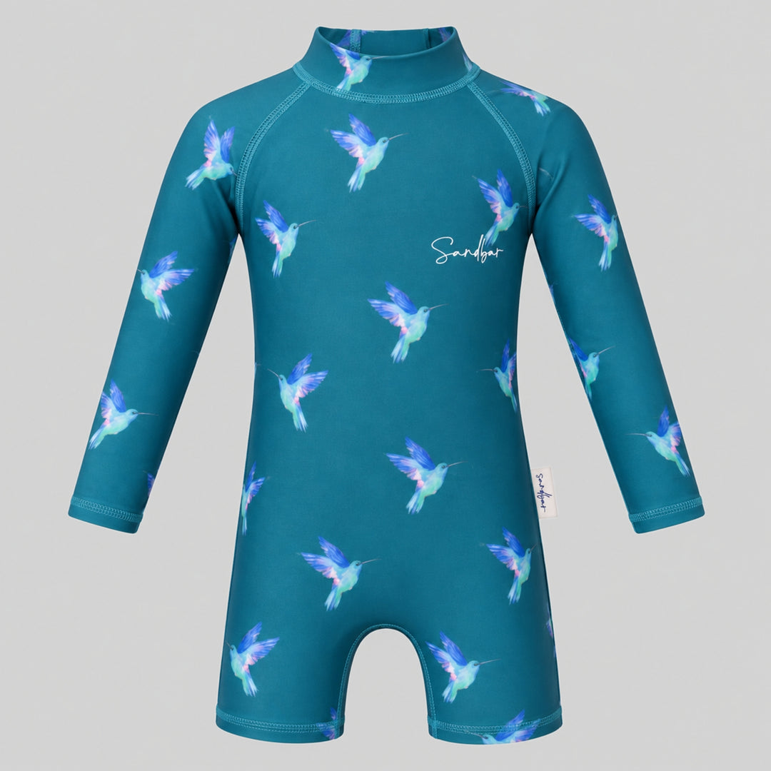Teal long-sleeve baby swimsuit with colourful hummingbird print, high neckline and short-leg design, shown on a light grey studio background.
