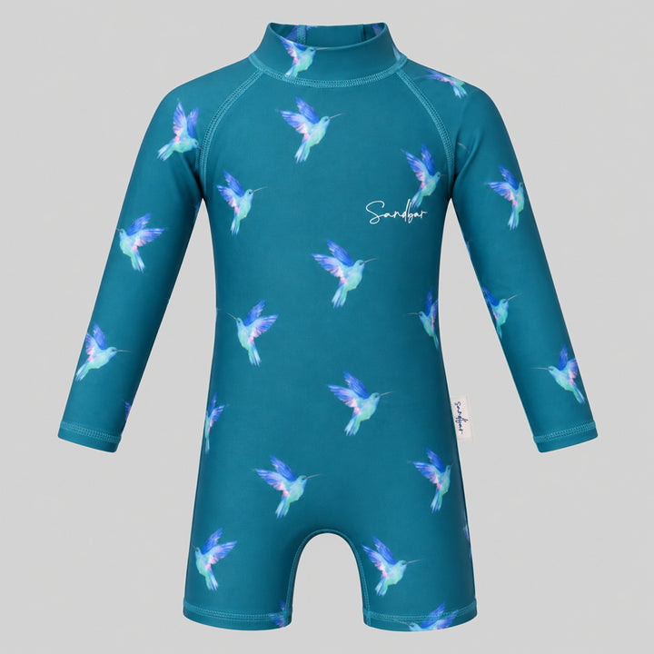 Teal long-sleeve baby swimsuit with colourful hummingbird print, high neckline and short-leg design, shown on a light grey studio background.
