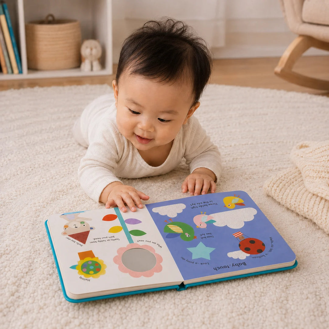 Baby lying on a carpeted floor reading a colorful book