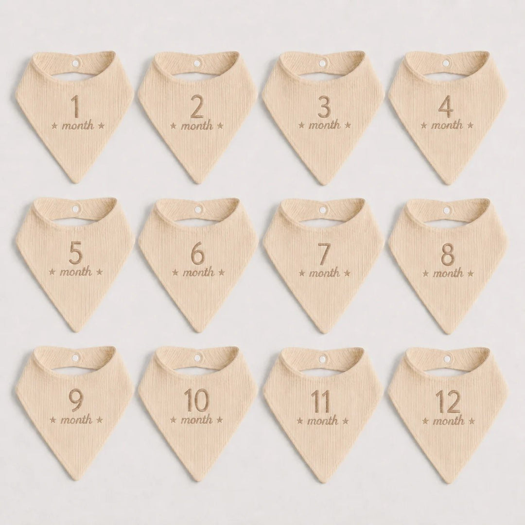 Set of 12 beige baby bandannas with month numbers on a light gray background