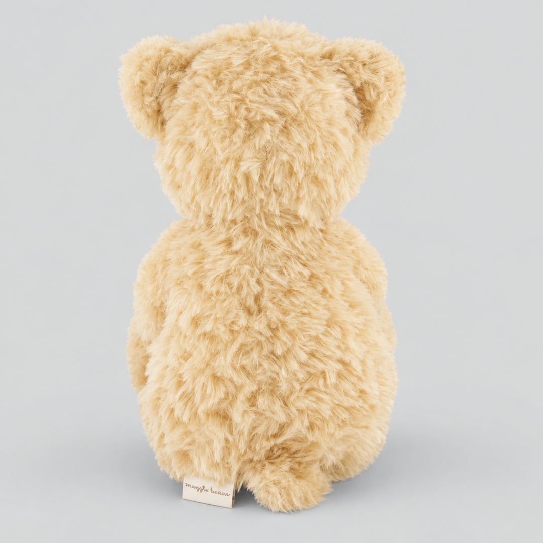 Rear view of a fluffy cream Arthur teddy bear showing its soft plush fur, rounded ears and small fabric label against a light grey studio background.