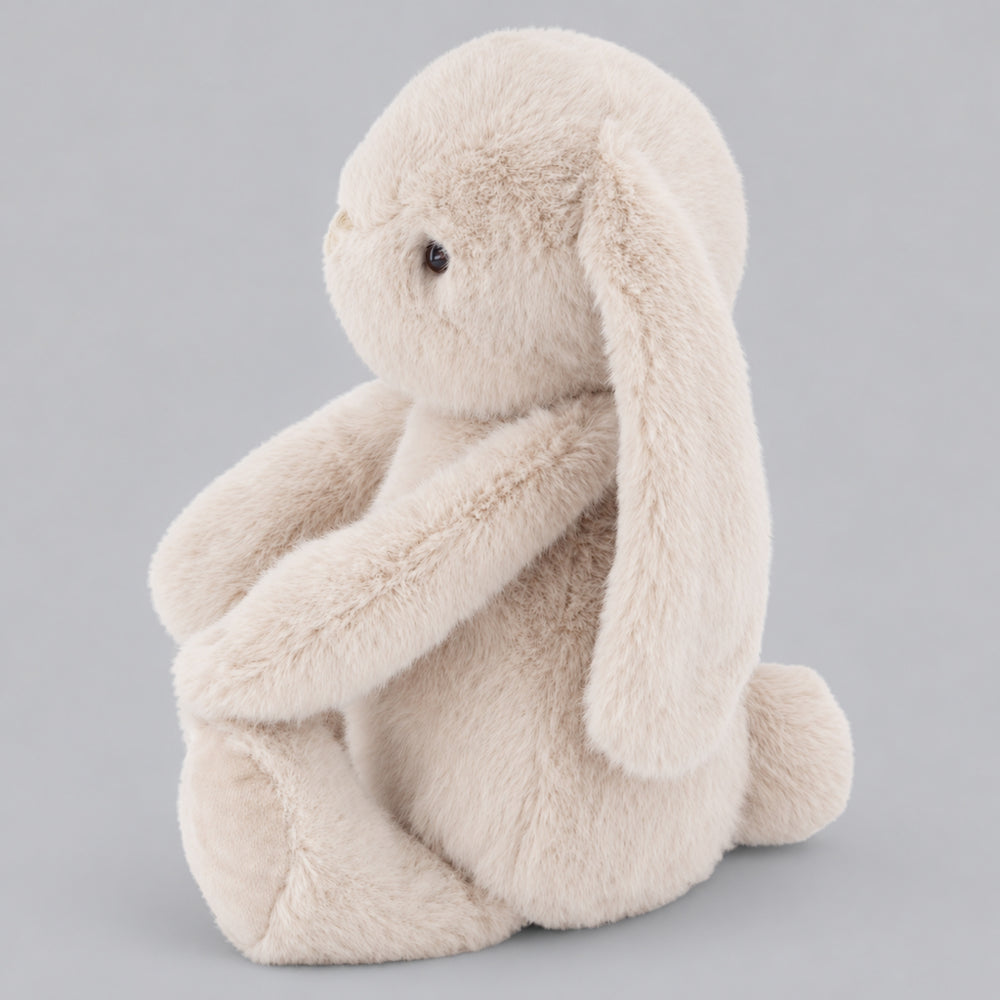 Beige Snuggle Bunnies plush bunny in side view on a light grey studio background.