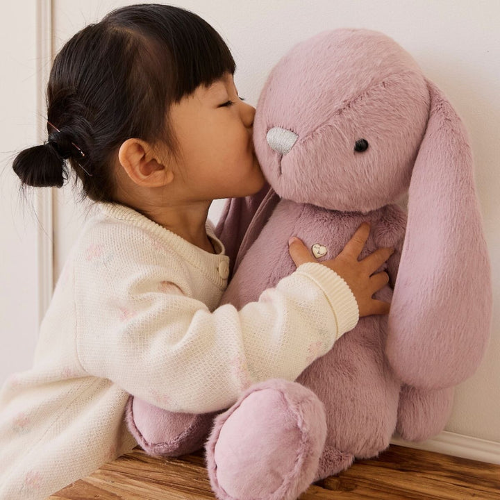 Young girl hugging and kissing a soft pink Snuggle Bunnies plush bunny.