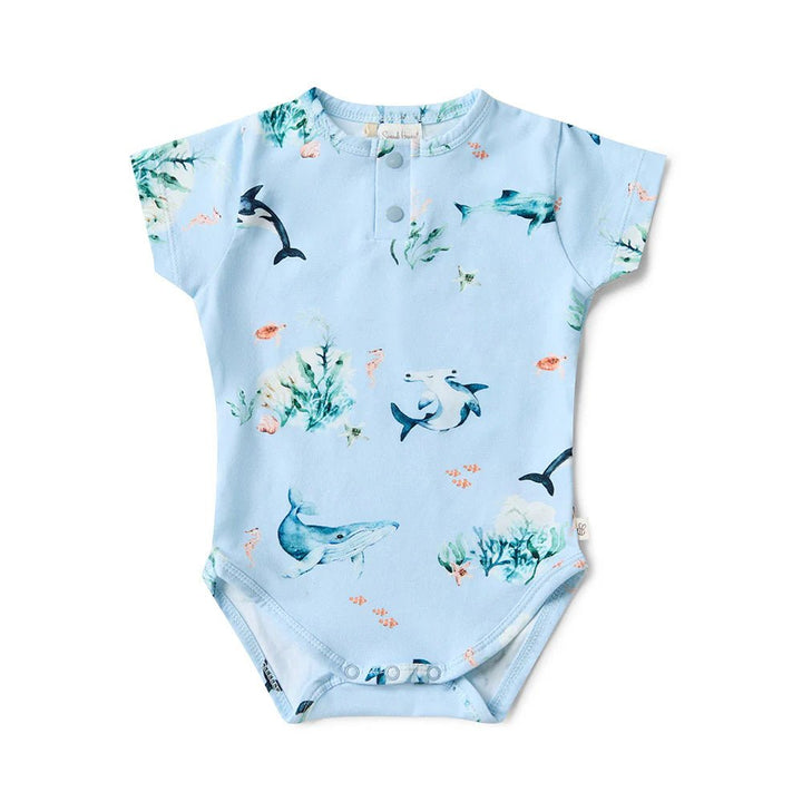 Baby onesie with shark and whale pattern on a light blue background
