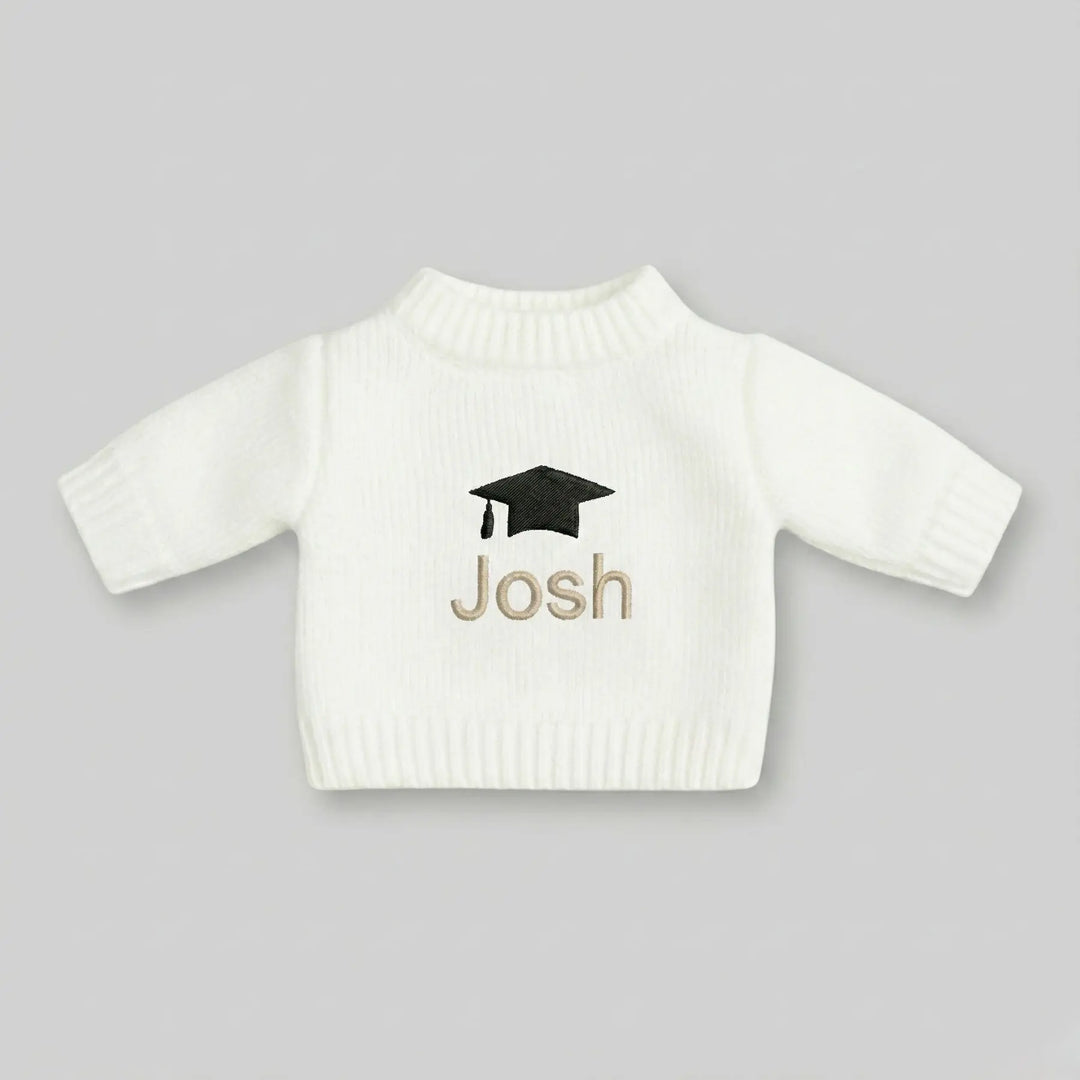 White sweater with 'Josh' and a graduation cap design on a gray background