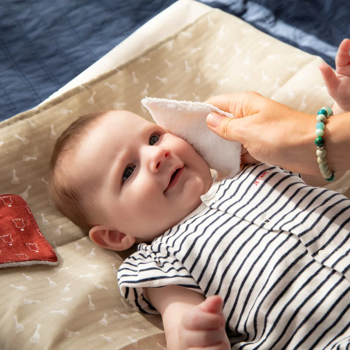 Parent Gently Cleaning Baby’s Face with Sophie la girafe Reusable Baby Wipe