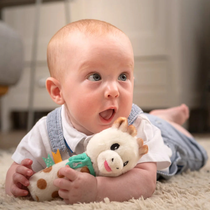 Baby Holding Sophie la girafe Pouet Rattle Toy on a Soft Play Mat