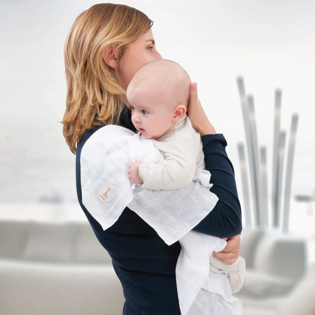 Mother Holding Baby with Sophie la girafe Muslin Swaddle Over Her Shoulder