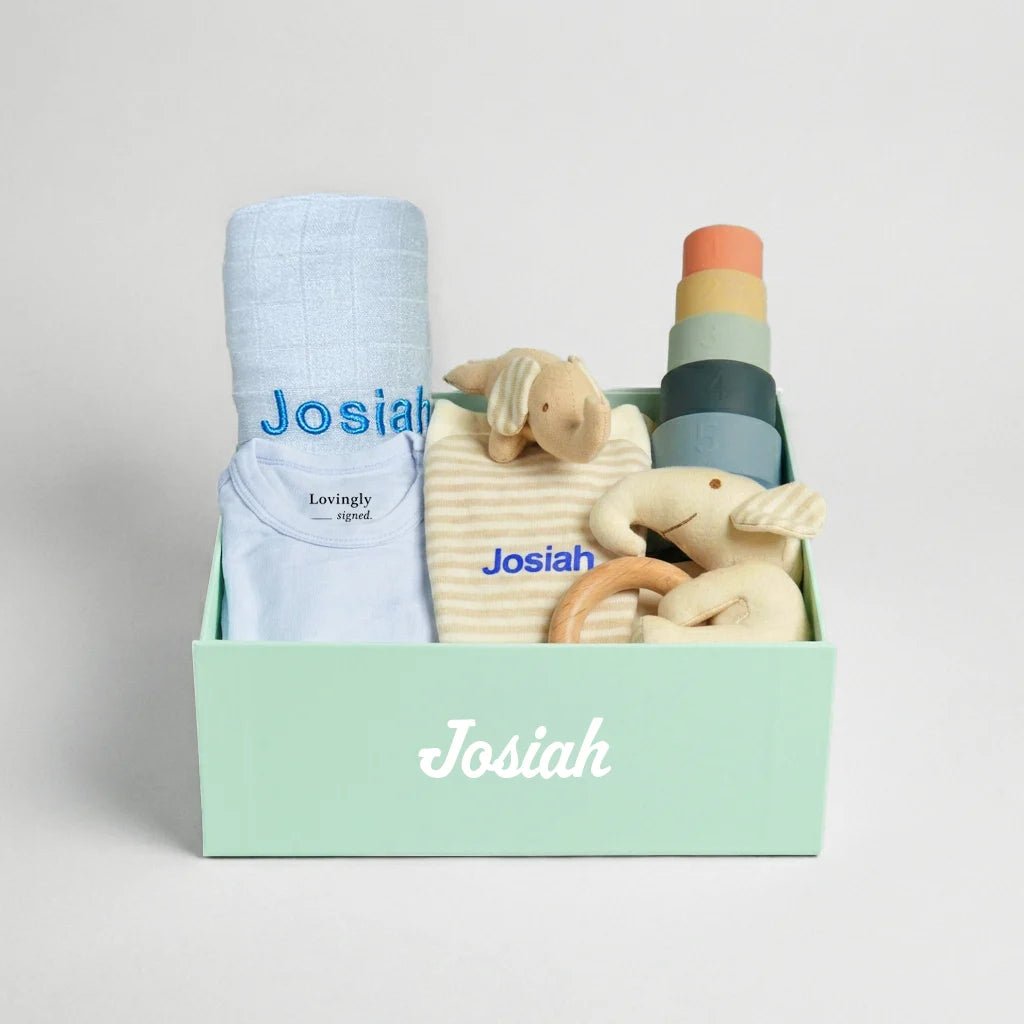 Blue Baby gift set with clothes, toys, and a blanket in a lovingly signed gift box