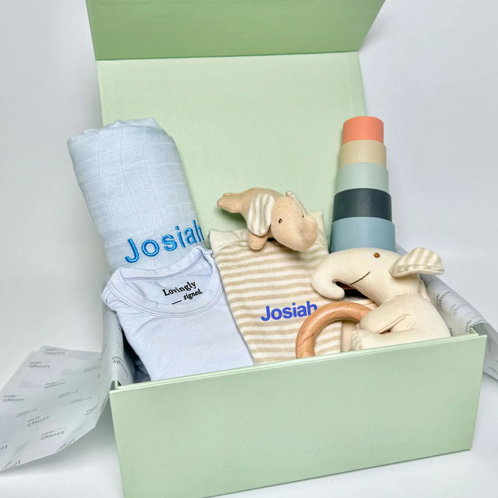 Blue Baby gift set with clothes, toys, and a blanket in a lovingly signed gift box