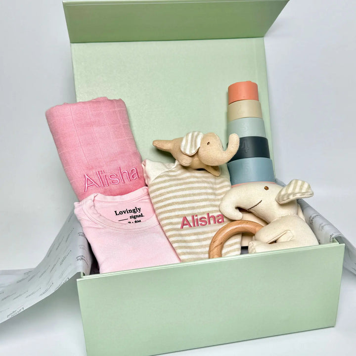 Pink Baby gift set with clothes, toys, and a blanket in a lovingly signed gift box