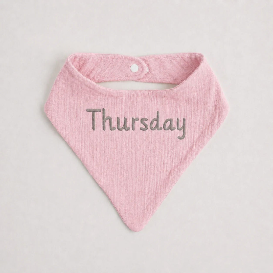 Pink baby bib with 'Thursday' text on a light gray background