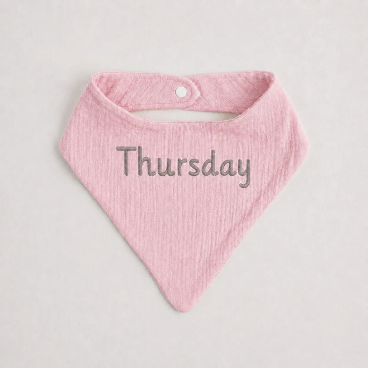 Pink baby bib with 'Thursday' text on a light gray background