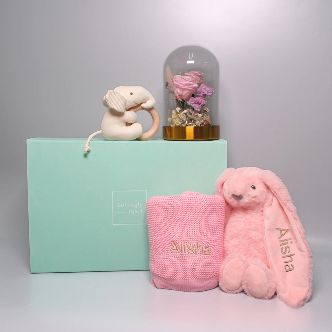 Pink unny soft toy, blanket, and elephant teether with a preserved flower bell jar. 