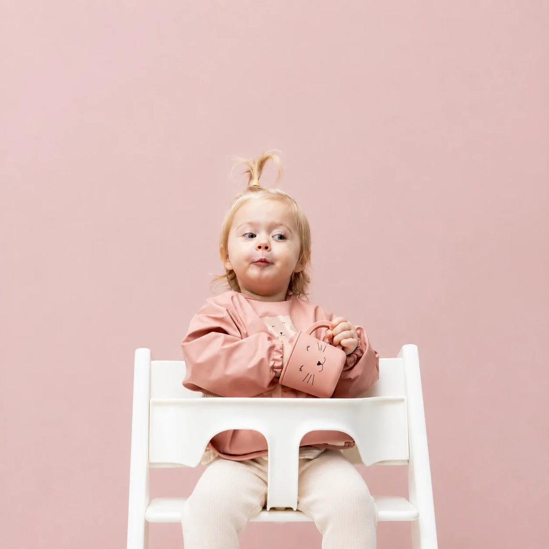 Toddler wearing Trixie Mrs Cat long sleeve waterproof bib during mealtime