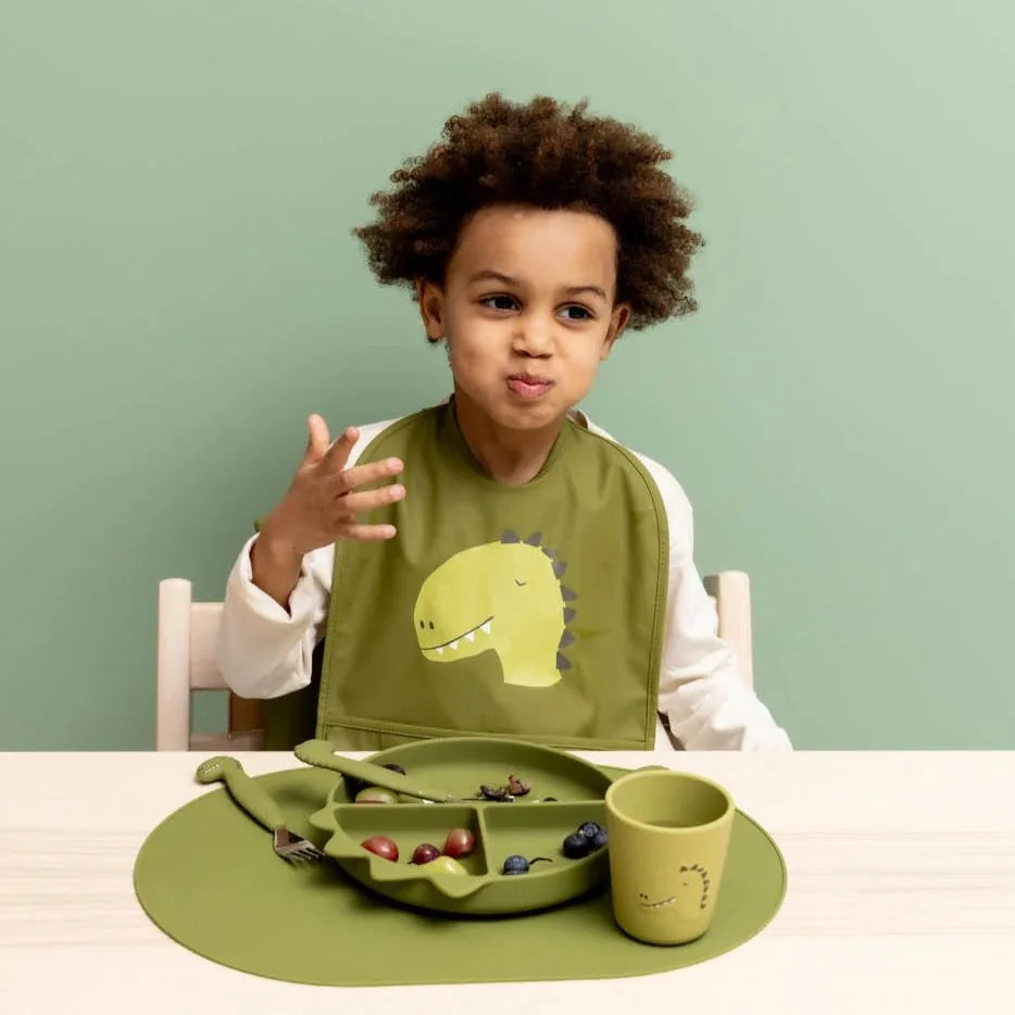Child wearing Trixie Mr Dino waterproof baby bib during mealtime