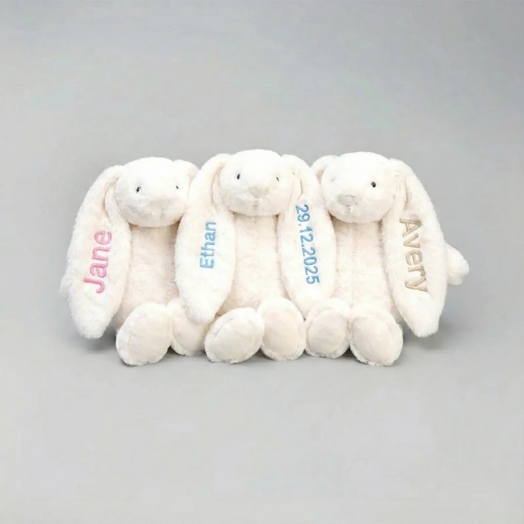 Three white plush bunnies with personalized names on a gray background