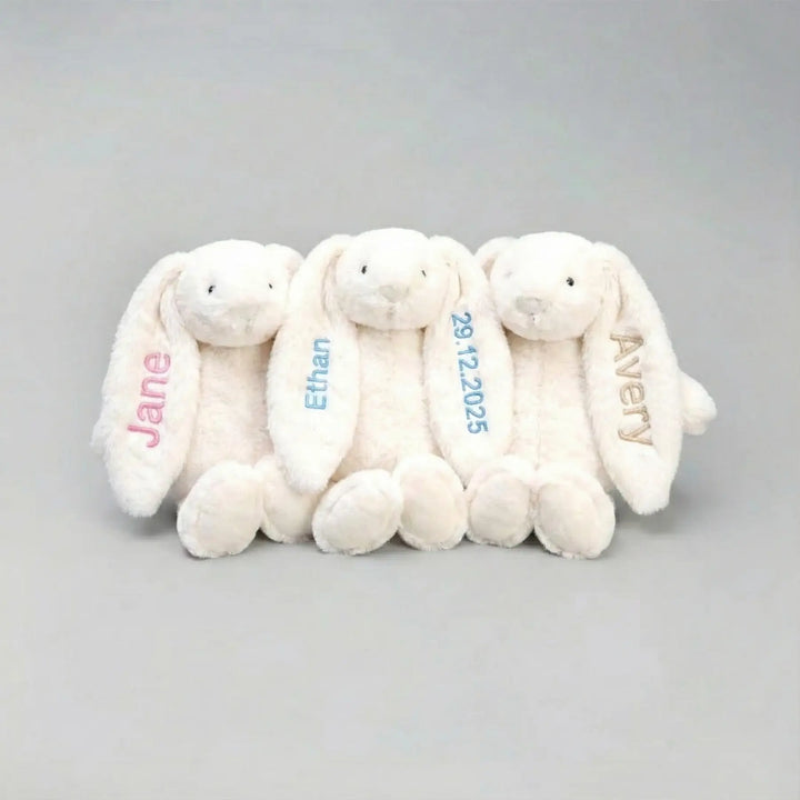 Three white plush bunnies with personalized names on a gray background
