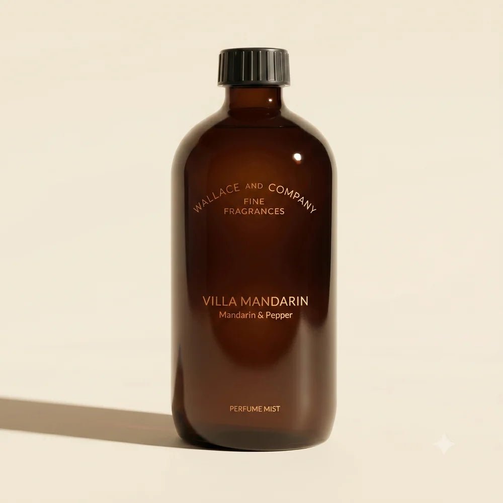 A dark amber glass bottle of Wallace and Company Villa Mandarin perfume mist, featuring a black cap and gold lettering, set against a warm beige background with a soft shadow.
