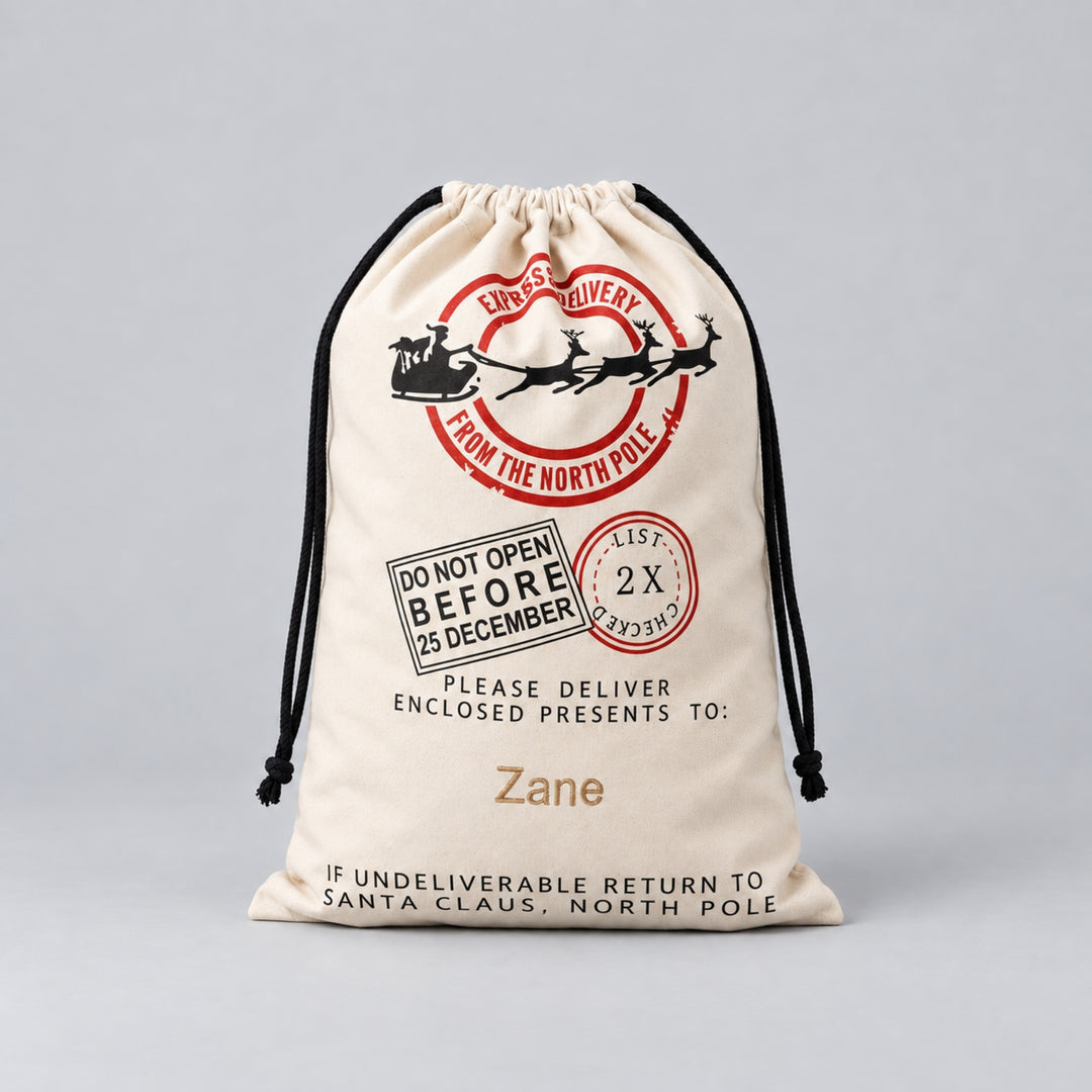 Cream Christmas drawstring sack with red and black North Pole Express sleigh and reindeer design, delivery stamps and the name “Zane” personalised in gold.