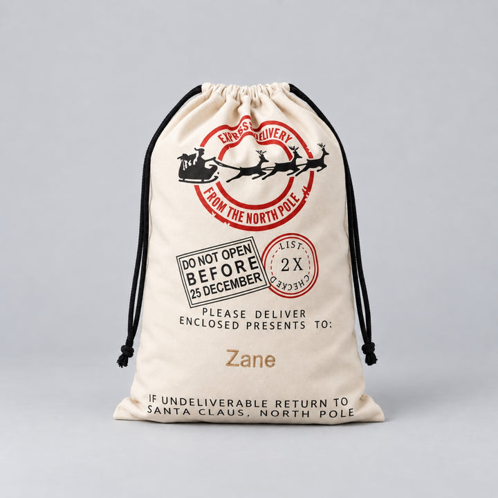 Cream Christmas drawstring sack with red and black North Pole Express sleigh and reindeer design, delivery stamps and the name “Zane” personalised in gold.