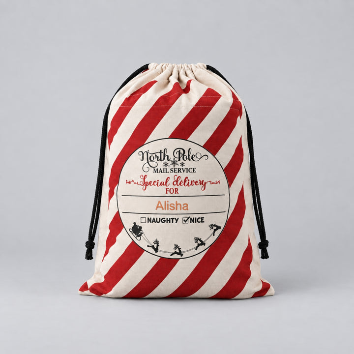 Cream Christmas drawstring sack with bold red candy-cane stripes, North Pole Mail Service special delivery label and the name “Alisha” personalised on the front.