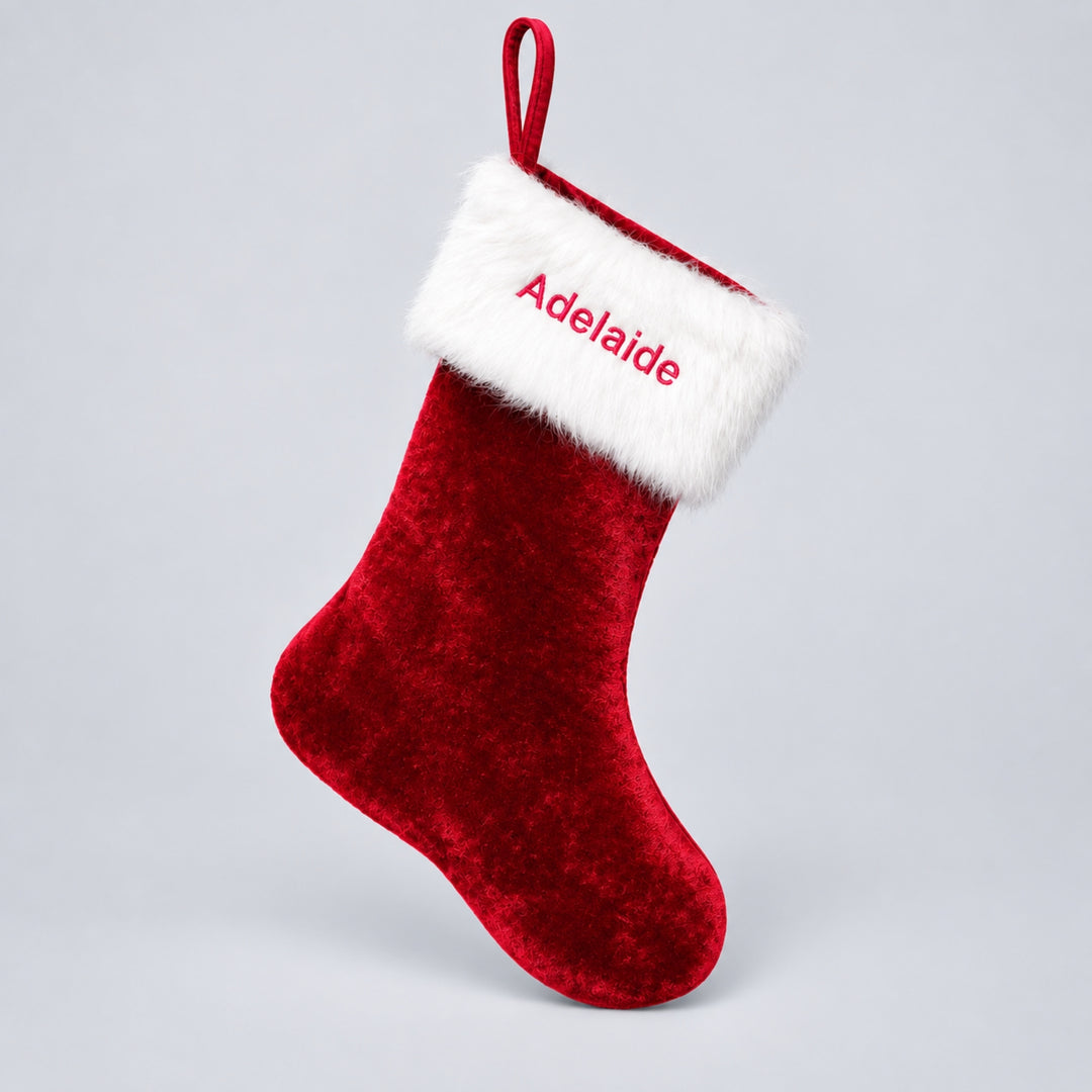Personalised red velvet Christmas stocking with a fluffy white cuff embroidered with the name “Adelaide” in red thread, finished with a red hanging loop.
