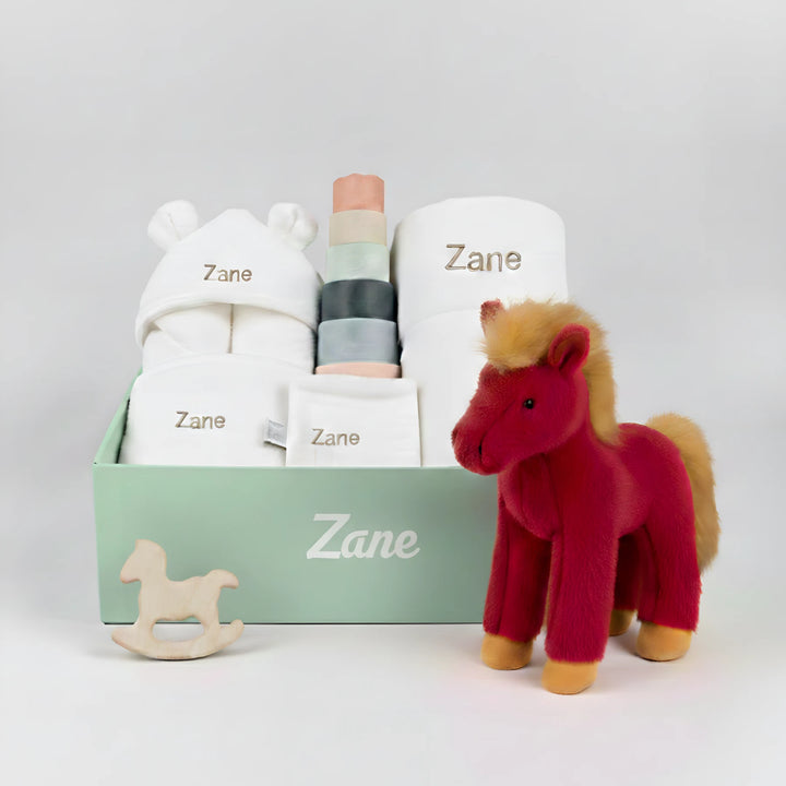 Baby gift set with Jellycat plush horse, personalised baby essentials and toys on a white background